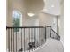 Elegant hallway with a curved staircase, iron railing, and large windows that provide natural light at 9207 Busaco Park Way, Winter Garden, FL 34787