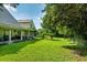 Large, grassy backyard featuring mature trees, an iron fence, and a covered patio at 9966 Hidden Dunes Ln, Orlando, FL 32832