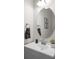 This bathroom features a round mirror, gray cabinets, and gray decorative towels and fixtures at 9966 Hidden Dunes Ln, Orlando, FL 32832