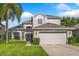 Charming two-story home with lush green lawn, landscaped garden, and attached two-car garage at 9966 Hidden Dunes Ln, Orlando, FL 32832