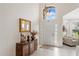 Bright foyer featuring white tiled floor, wooden furniture, and a view into the living room at 9966 Hidden Dunes Ln, Orlando, FL 32832