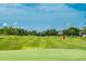 Scenic view of a well maintained golf course with a bright red flag and lush green landscape at 9966 Hidden Dunes Ln, Orlando, FL 32832