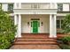 Inviting entrance with a bright green door, brick pathway, white columns, and classic wall-mounted lanterns at 1011 Lake Davis Dr, Orlando, FL 32806