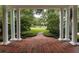 Covered porch with brick flooring and white columns framing a serene view of the lush front yard at 1011 Lake Davis Dr, Orlando, FL 32806