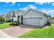 View of a well-kept one-story home with a two-car garage, lovely landscaping, and a brick-paved driveway at 1061 Castlevecchio Loop, Orlando, FL 32825