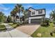 Lovely two-story home featuring a brick driveway, well-manicured lawn, palm trees, and a charming covered porch at 10640 Tibbett St, Orlando, FL 32832