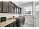 Laundry room with granite countertops, dark cabinets, a window, and stainless steel washer and dryer at 10640 Tibbett St, Orlando, FL 32832