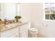Bright bathroom featuring a granite countertop vanity and toilet with window view at 1545 Fairview Cir, Reunion, FL 34747