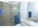 Bathroom with neutral tile, glass shower doors, granite counters, and blue towel accent at 1545 Fairview Cir, Reunion, FL 34747