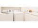 Bright laundry room with white washer and dryer plus a sink with storage at 1545 Fairview Cir, Reunion, FL 34747