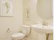 Compact powder room with pedestal sink, toilet, decorative prints, and round mirror at 1774 Pasture Loop, Oviedo, FL 32765