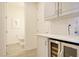 An elegant bathroom featuring white cabinetry, subway tile backsplash, and a convenient wine refrigerator at 1774 Pasture Loop, Oviedo, FL 32765
