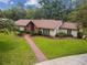Inviting single-story home with mature trees, manicured lawn, and brick walkway at 207 S Sweetwater Blvd, Longwood, FL 32779