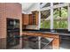 Close up of kitchen with island cooktop, granite counters, and brick accent wall at 207 S Sweetwater Blvd, Longwood, FL 32779
