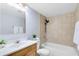 Well-lit bathroom featuring a shower over tub with neutral tiles, new shower head and a wooden vanity at 208 Scottsdale Sq # 208, Winter Park, FL 32792