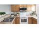 Well-lit kitchen with wood cabinets, modern microwave, and clean white oven range at 208 Scottsdale Sq # 208, Winter Park, FL 32792