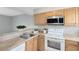 Functional kitchen featuring wood cabinetry, white appliances, and modern microwave at 208 Scottsdale Sq # 208, Winter Park, FL 32792