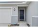Close-up of a stylish front door and a spacious two-car garage at 232 Summerlin Loop, Haines City, FL 33844