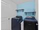 Functional laundry room with blue walls, shelving, and modern washer and dryer units at 232 Summerlin Loop, Haines City, FL 33844
