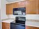 A bright kitchen features wooden cabinets, black appliances, and white countertops with a tile backsplash at 2422 Condado Ct, Kissimmee, FL 34743