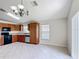 Bright kitchen features wood cabinetry, black appliances, a chandelier, and tile flooring with neutral walls at 2422 Condado Ct, Kissimmee, FL 34743