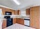 A bright kitchen features wooden cabinets, tile flooring, black appliances, and white countertops and backsplash at 2422 Condado Ct, Kissimmee, FL 34743