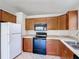 A bright kitchen features wooden cabinets, tile flooring, black appliances, and white countertops and backsplash at 2422 Condado Ct, Kissimmee, FL 34743