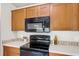 A bright kitchen features wooden cabinets, black appliances, and white countertops with a tile backsplash at 2422 Condado Ct, Kissimmee, FL 34743