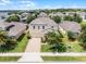 Aerial view of a home in a residential neighborhood, featuring a well-maintained lawn and brick driveway at 2432 Riviera Ln, Minneola, FL 34715