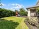 A lush backyard featuring a wooden playset with a slide surrounded by green grass and privacy hedges at 2432 Riviera Ln, Minneola, FL 34715