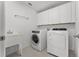 Convenient laundry room equipped with modern washer, dryer, sink, and ample cabinet space at 2432 Riviera Ln, Minneola, FL 34715