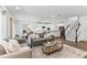 Open-concept living room featuring a modern couch, view into the kitchen, and stairs to the upper level at 2432 Riviera Ln, Minneola, FL 34715