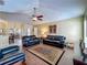 Spacious open-concept living room with ceiling fan, opens to dining area, dark leather sofas, and tile floor at 2558 Ballard Ave, Orlando, FL 32833