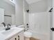 Modern bathroom with a white vanity, dark fixtures, and a tiled shower-tub at 2823 Ne 24Th Pl, Ocala, FL 34470