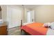 A cozy bedroom featuring wood-look flooring, triple closet, and an orange quilt at 31961 Redtail Reserve Blvd, Sorrento, FL 32776