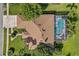 An aerial view showcases a home with a brown roof and screened pool, surrounded by lush landscaping and greenery at 3713 Ocita Dr, Orlando, FL 32837