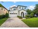 Elegant white brick home featuring an attached garage, lush lawn, and a welcoming paved driveway at 528 Greely St, Orlando, FL 32804