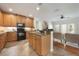 A kitchen with wooden cabinets, an island with a breakfast bar, and black appliances offers a modern aesthetic at 5350 Penway Dr, Orlando, FL 32814