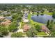 An aerial view of a neighborhood with houses, green trees, lawns, and a pond with a lake in the distance at 700 Wyckliffe Pl, Winter Springs, FL 32708