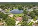 Aerial view of home by a lake surrounded by lush landscaping and mature trees at 700 Wyckliffe Pl, Winter Springs, FL 32708