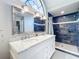 Bathroom featuring a double sink vanity with granite countertop and walk-in shower with blue subway tile at 700 Wyckliffe Pl, Winter Springs, FL 32708