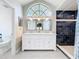 Bathroom with double sink vanity, large framed mirror, shower, and arched window providing natural light at 700 Wyckliffe Pl, Winter Springs, FL 32708