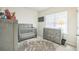 Neutral baby bedroom featuring grey colored crib, dresser and rug, with natural light at 730 Rominger Loop, Apopka, FL 32712