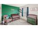 Bedroom design with green accent wall, wood crib, and rocking chair with forest themed decor at 7603 Taormina Way, Clermont, FL 34714