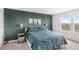 Cozy bedroom featuring a king-size bed with a dark green comforter, accent wall and natural light at 7603 Taormina Way, Clermont, FL 34714