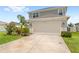 Two car garage with an extensive driveway and manicured lawn at 7603 Taormina Way, Clermont, FL 34714