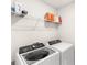 Laundry room with front load washer, dryer, and wire rack shelving at 7603 Taormina Way, Clermont, FL 34714