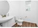 Simple half bathroom with white fixtures, wood-look floor and circular mirror above the sink at 812 Benoi Dr, Davenport, FL 33896