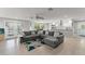 Bright open-concept area featuring a gray sectional sofa, tile floors, and access to the kitchen and backyard at 945 Shawna Shrs, Haines City, FL 33844