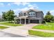 A pristine two-story home sits on a manicured lawn with beautiful landscape and a brick driveway at 15900 Citrus Knoll Dr, Winter Garden, FL 34787